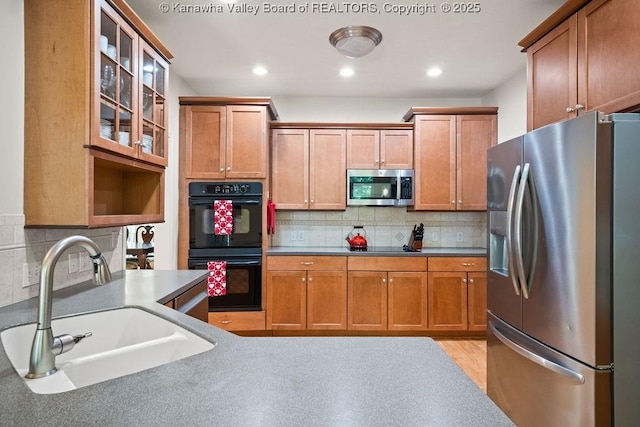16 Pinnacle Dr, Charleston, WV 25311 - kitchen featuring stainless steel appliances, a sink, glass insert cabinets, decorative backsplash, and brown cabinetry