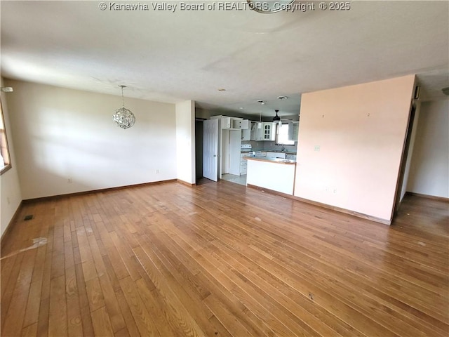 1605 Dunbar Ave, Dunbar, WV 25064 - unfurnished living room with light wood finished floors, baseboards, and a chandelier