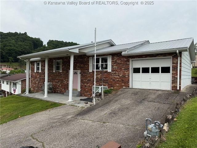 40 Hickory Ln, Madison, WV 25130 - view of front of house with an attached garage, asphalt driveway, brick siding, metal roof, and a front yard
