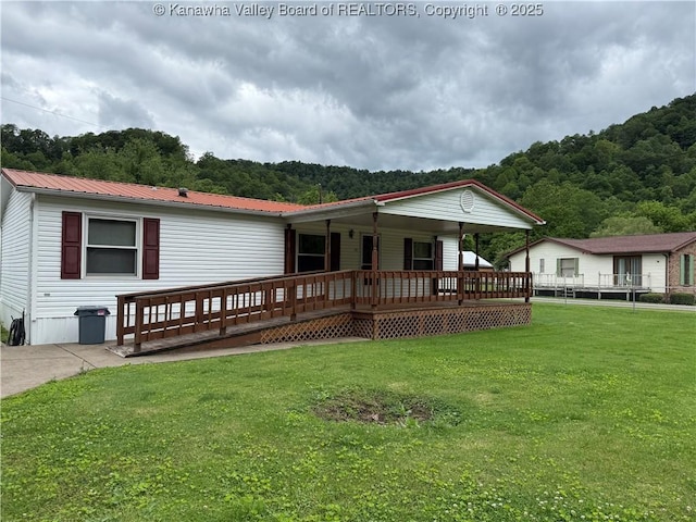 12 Brewster Dr, Chapmanville, WV 25508 - view of front of property featuring a front yard, covered porch, metal roof, and a forest view