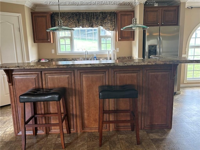 30 Beech Ln, Madison, WV 25130 - kitchen with crown molding, stainless steel refrigerator with ice dispenser, a kitchen bar, decorative light fixtures, and dark stone counters