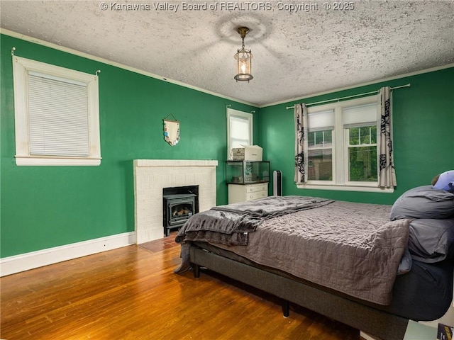 657 Beech Ave, Charleston, WV 25302 - bedroom with wood finished floors, crown molding, a wood stove, a textured ceiling, and baseboards