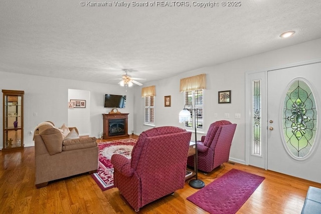 108 Lock Ln, Alum Creek, WV 25003 - living room with a textured ceiling, wood finished floors, a glass covered fireplace, and a ceiling fan