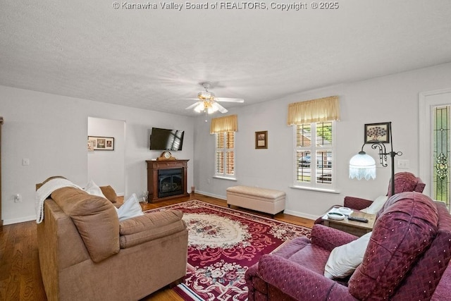108 Lock Ln, Alum Creek, WV 25003 - living area with wood finished floors, a ceiling fan, a glass covered fireplace, and baseboards