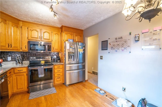 400 13th St, Dunbar, WV 25064 - kitchen with stainless steel appliances, light wood-style floors, backsplash, brown cabinetry, and a textured ceiling