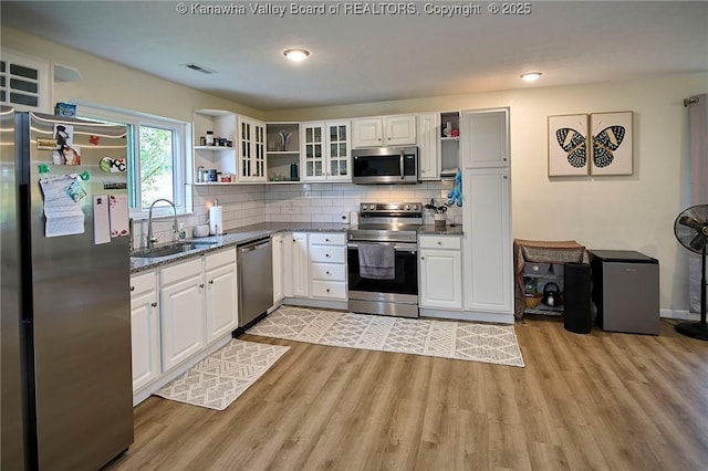 5201 Hammons Dr, Charleston, WV 25313 - kitchen featuring appliances with stainless steel finishes, open shelves, a sink, light wood-style flooring, and dark stone countertops