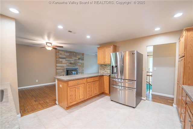 102 Utah Hollow Rd, Charleston, WV 25312 - kitchen with stainless steel fridge with ice dispenser, a stone fireplace, a peninsula, ceiling fan, and baseboards