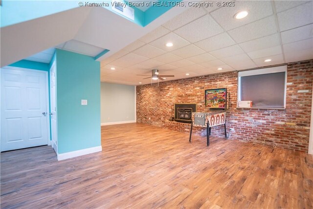 102 Utah Hollow Rd, Charleston, WV 25312 - living area featuring brick wall, wood finished floors, a wood stove, baseboards, and a drop ceiling