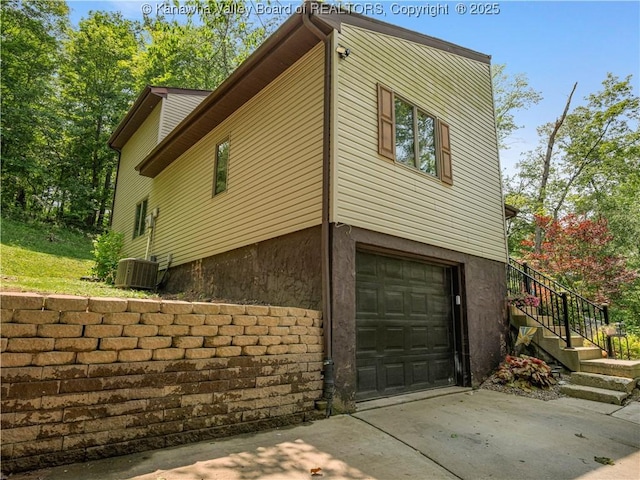 26 Banister Dr, Cross Lanes, WV 25313 - view of property exterior featuring a garage, concrete driveway, stairs, and central air condition unit