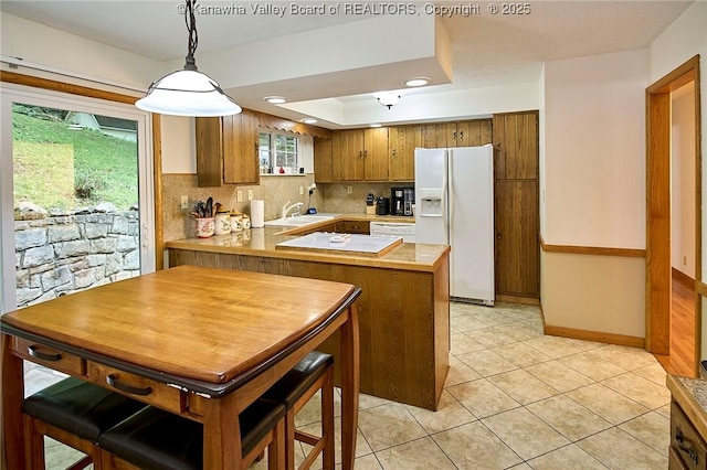 205 Autumn Dr, Dunbar, WV 25064 - kitchen featuring white appliances, light countertops, brown cabinetry, a peninsula, and tasteful backsplash