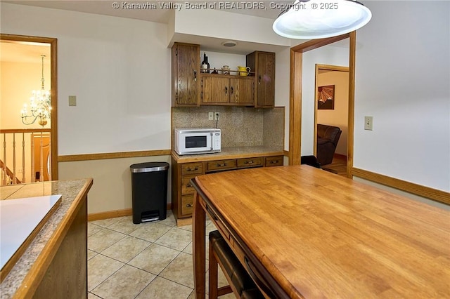 205 Autumn Dr, Dunbar, WV 25064 - kitchen with white microwave, a chandelier, decorative backsplash, brown cabinets, and baseboards