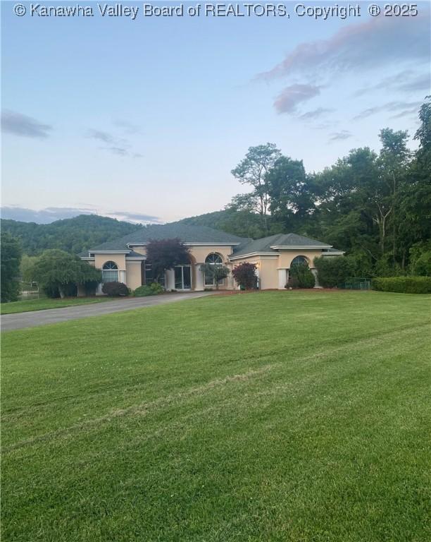 11 Larabee Ln, Winfield, WV 25213 - view of front of house with asphalt driveway, a front lawn, and stucco siding