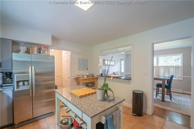 1418 Sweetbrier Rd, Charleston, WV 25314 - kitchen featuring stainless steel fridge, light tile patterned floors, light stone countertops, a center island, and baseboards