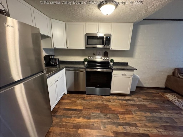 2106 Kanawha Blvd E Unit 322, Charleston, WV 25311 - kitchen with appliances with stainless steel finishes, dark countertops, dark wood-type flooring, white cabinetry, and a textured ceiling