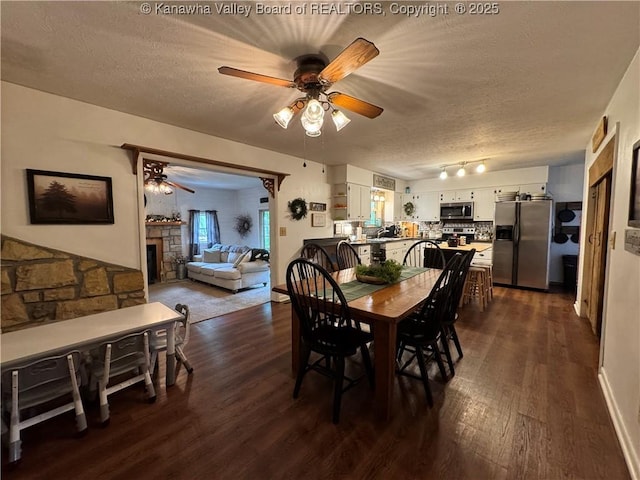 3902 Poca River Rd S, Poca, WV 25159 - dining space with a textured ceiling, a ceiling fan, dark wood finished floors, and a stone fireplace