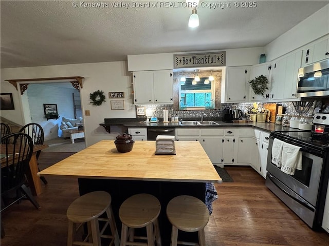3902 Poca River Rd S, Poca, WV 25159 - kitchen featuring stainless steel appliances, dark wood-type flooring, a kitchen breakfast bar, white cabinetry, and decorative backsplash