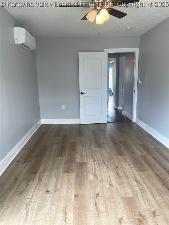 517 16th St, Dunbar, WV 25064 - spare room featuring an AC wall unit, wood finished floors, a ceiling fan, and baseboards