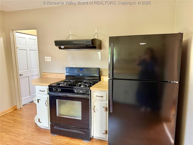300 Sycamore St, Ravenswood, WV 26164 - kitchen with freestanding refrigerator, black gas stove, range hood, white cabinetry, and light wood finished floors