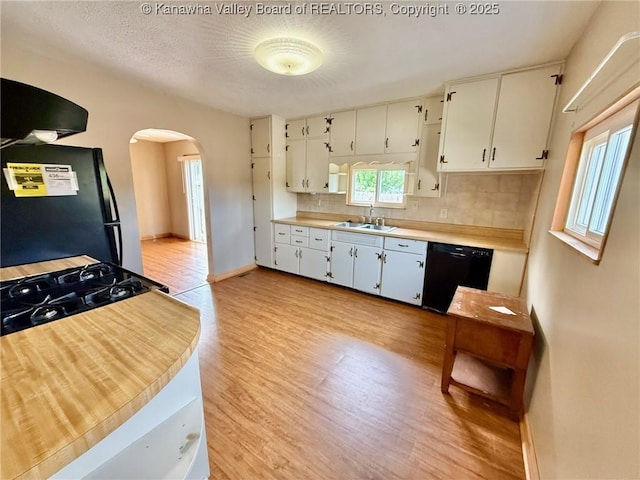300 Sycamore St, Ravenswood, WV 26164 - kitchen with black appliances, a sink, arched walkways, light wood-style floors, and backsplash