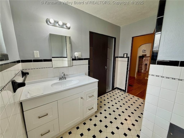 300 Sycamore St, Ravenswood, WV 26164 - bathroom featuring tile walls, vanity, a textured ceiling, and wainscoting