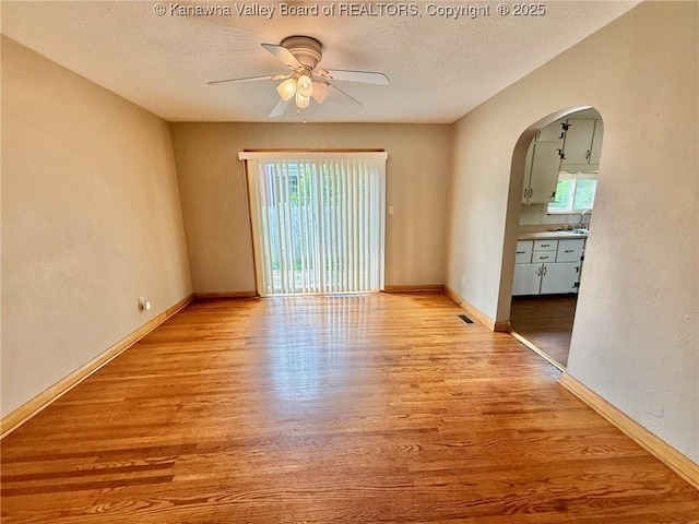 300 Sycamore St, Ravenswood, WV 26164 - spare room with ceiling fan, arched walkways, light wood-type flooring, a textured ceiling, and baseboards
