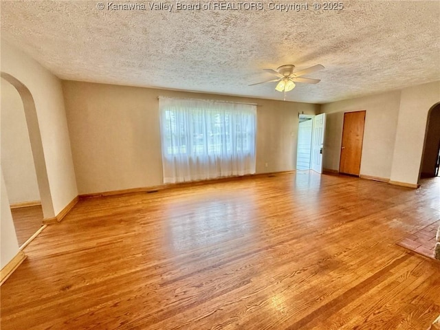 300 Sycamore St, Ravenswood, WV 26164 - unfurnished room featuring arched walkways, wood finished floors, a ceiling fan, a textured ceiling, and baseboards