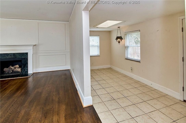4302 Virginia Ave, Charleston, WV 25304 - unfurnished living room with baseboards, a premium fireplace, light wood-style flooring, and a skylight
