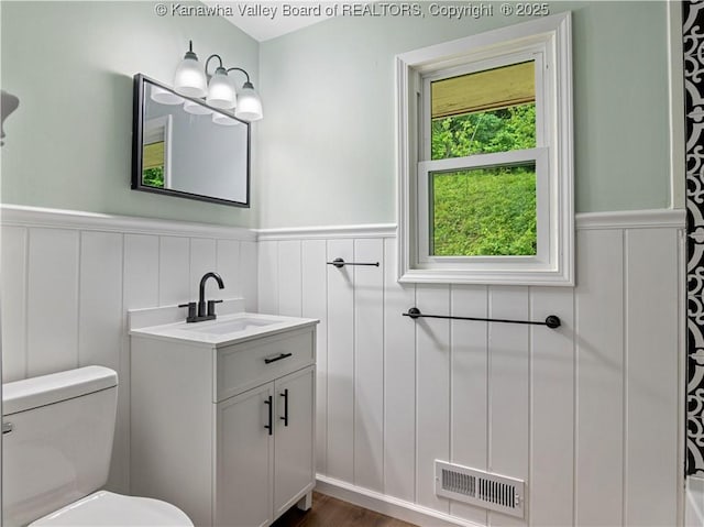 1255 Park Ave, Charleston, WV 25302 - bathroom with vanity, a wainscoted wall, toilet, a decorative wall, and wood finished floors