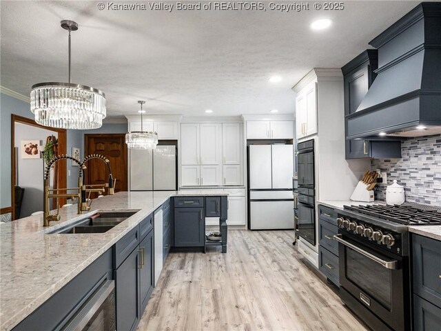123 Brooke St, Culloden, WV 25510 - kitchen featuring appliances with stainless steel finishes, wall chimney range hood, a sink, tasteful backsplash, and white cabinetry