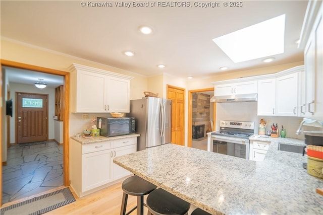 868 Alta Rd, Charleston, WV 25314 - kitchen featuring appliances with stainless steel finishes, under cabinet range hood, a skylight, backsplash, and recessed lighting