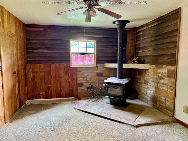 3112 Cicerone Rd, Charleston, WV 25320 - unfurnished living room with a wood stove, wooden walls, ceiling fan, a textured ceiling, and carpet floors