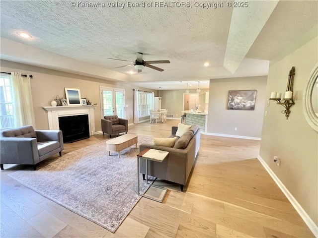 90 Brooke St, Culloden, WV 25510 - living room with a textured ceiling, a ceiling fan, light wood-style flooring, baseboards, and a fireplace with flush hearth