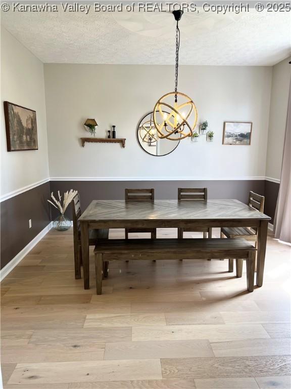90 Brooke St, Culloden, WV 25510 - dining area featuring a chandelier, light wood-style flooring, a textured ceiling, and baseboards