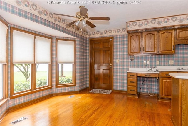 112 Willowood Cir, Hurricane, WV 25526 - kitchen featuring wallpapered walls, light wood-type flooring, brown cabinetry, light countertops, and baseboards