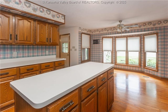 112 Willowood Cir, Hurricane, WV 25526 - kitchen featuring wallpapered walls, light countertops, brown cabinetry, and light wood-style flooring