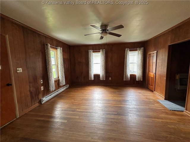 386 Maple St, Mason, WV 25260 - empty room featuring a baseboard heating unit, plenty of natural light, hardwood / wood-style floors, and wood walls