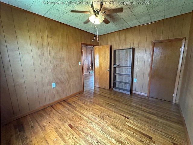386 Maple St, Mason, WV 25260 - empty room with wood finished floors, a ceiling fan, wooden walls, and baseboards