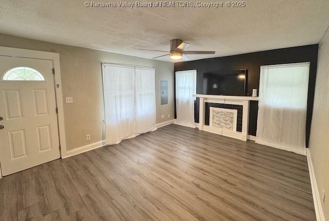 547 Garrison Ave, Charleston, WV 25302 - unfurnished living room featuring a textured ceiling, wood finished floors, a ceiling fan, baseboards, and a tile fireplace