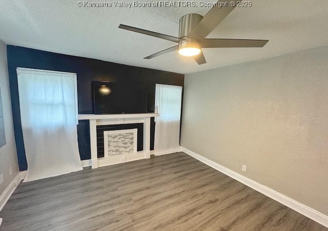 547 Garrison Ave, Charleston, WV 25302 - unfurnished living room with wood finished floors, a ceiling fan, a fireplace with raised hearth, a textured ceiling, and baseboards