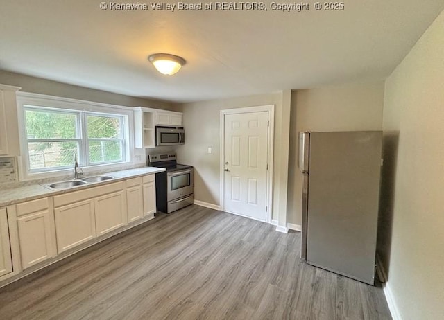 547 Garrison Ave, Charleston, WV 25302 - kitchen with stainless steel appliances, a sink, light wood finished floors, light countertops, and baseboards