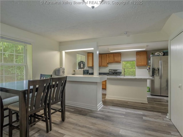 3742 Greenview Rd, South Charleston, WV 25309 - kitchen featuring stainless steel refrigerator with ice dispenser, brown cabinetry, a textured ceiling, wood finished floors, and light countertops