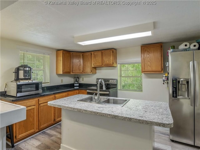 3742 Greenview Rd, South Charleston, WV 25309 - kitchen with appliances with stainless steel finishes, light wood-type flooring, brown cabinetry, and plenty of natural light