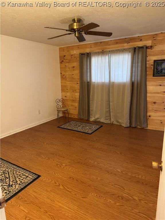 194 Shawnee Ests, Winfield, WV 25213 - spare room featuring wood walls, a ceiling fan, and wood finished floors