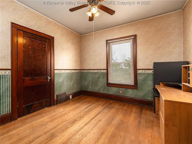 412 C St, Saint Albans, WV 25177 - unfurnished room featuring light wood finished floors, ceiling fan, wainscoting, wallpapered walls, and crown molding