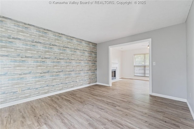 1571 Thistlewood Cir, Hurricane, WV 25526 - unfurnished living room featuring an accent wall, wallpapered walls, a glass covered fireplace, and wood finished floors
