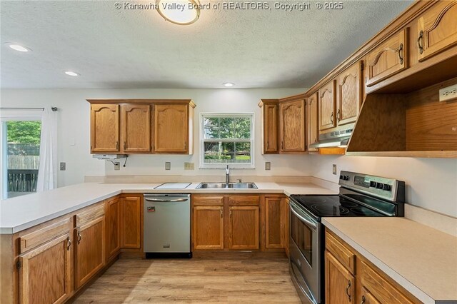 1571 Thistlewood Cir, Hurricane, WV 25526 - kitchen with appliances with stainless steel finishes, under cabinet range hood, healthy amount of natural light, a peninsula, and a textured ceiling