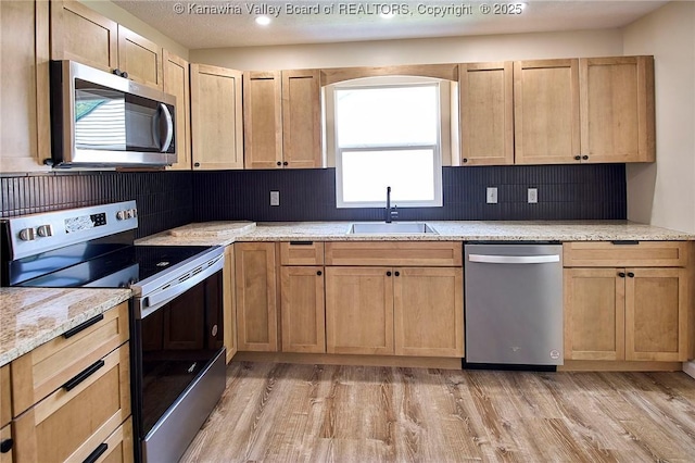 911 Dupont Ave, Nitro, WV 25143 - kitchen featuring appliances with stainless steel finishes, light wood finished floors, decorative backsplash, light brown cabinets, and light stone countertops