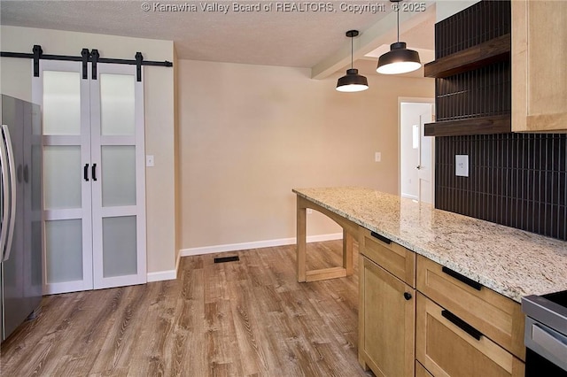 911 Dupont Ave, Nitro, WV 25143 - kitchen with a barn door, light wood-style flooring, freestanding refrigerator, hanging light fixtures, and light stone countertops
