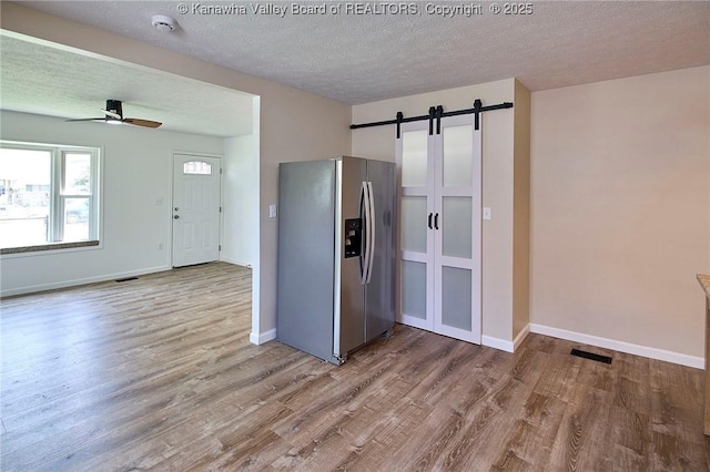 911 Dupont Ave, Nitro, WV 25143 - kitchen featuring stainless steel refrigerator with ice dispenser, a barn door, wood finished floors, a textured ceiling, and ceiling fan