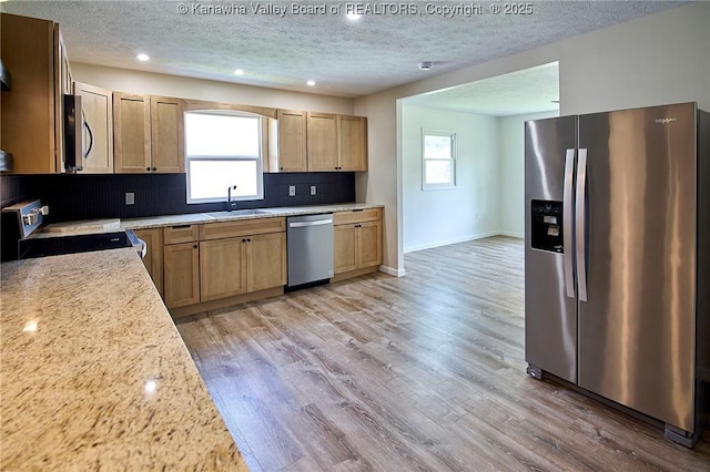 911 Dupont Ave, Nitro, WV 25143 - kitchen with appliances with stainless steel finishes, a textured ceiling, tasteful backsplash, light wood-style floors, and light brown cabinetry